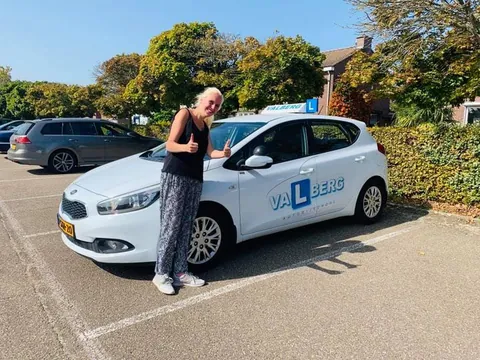 Leerling viert het behalen van het rijbewijs bij de lesauto