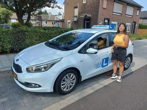 Blije geslaagde cursist bij de lesauto voor het examencentrum