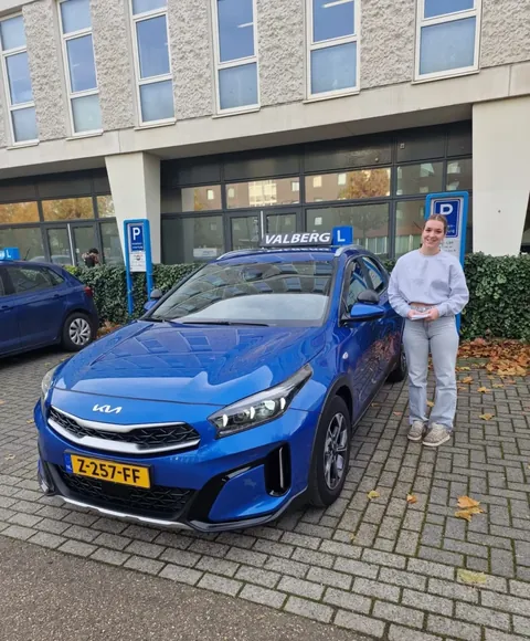 Kayli is geslaagd voor haar rijbewijs en staat bij de lesauto